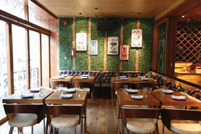 Dining room with wooden tables, a green wall with framed prints and large windows