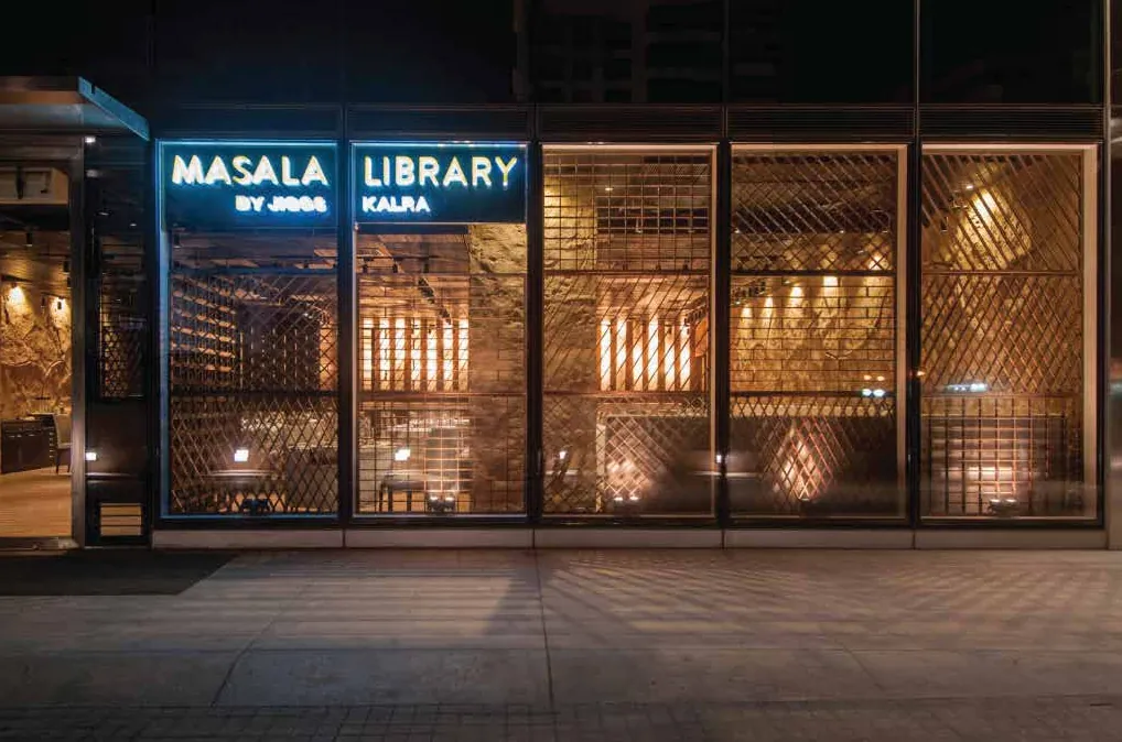 Masala Library storefront at night, blue neon signage over glowing lattice windows