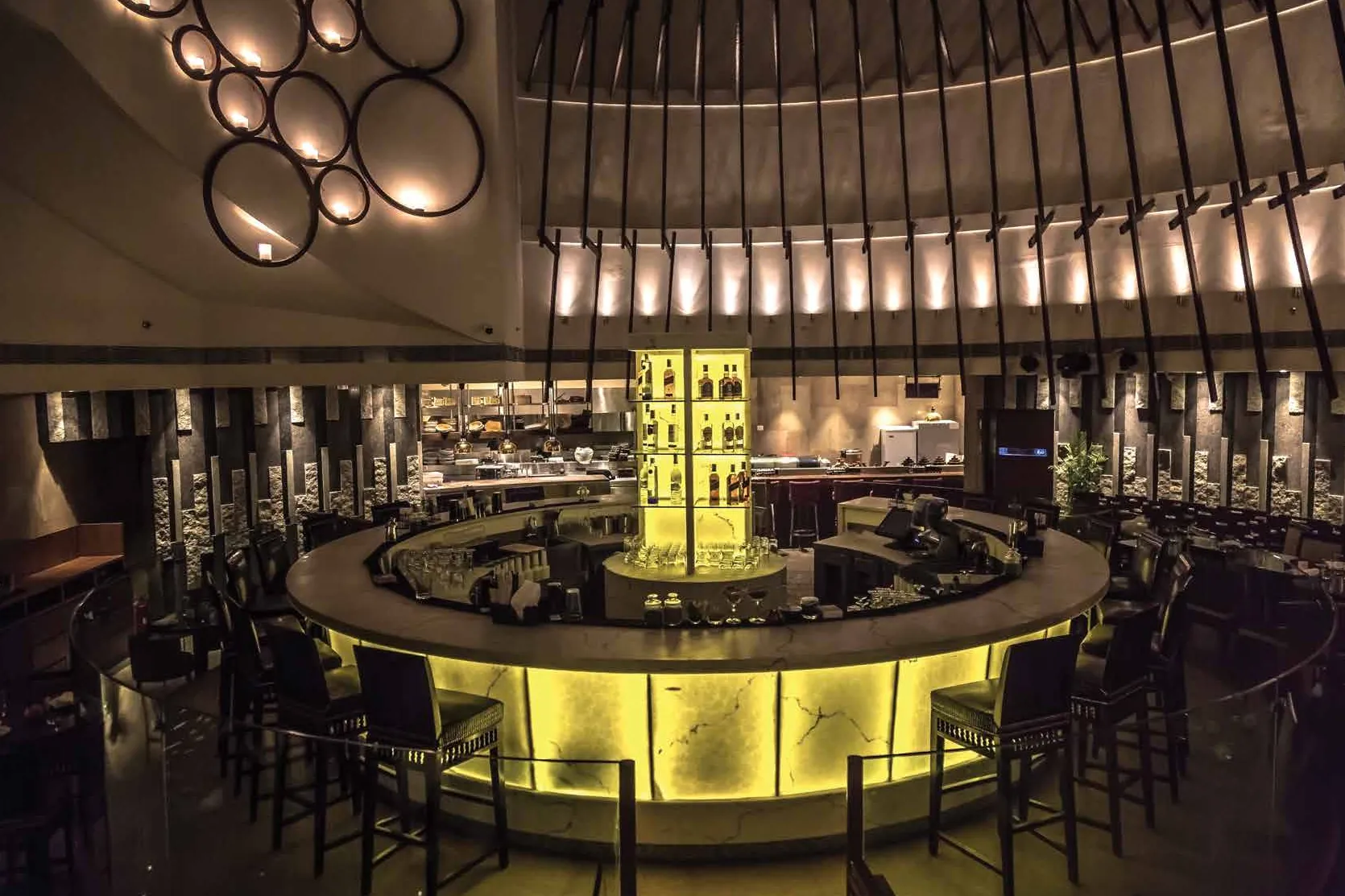 Pa Pa Ya's circular backlit yellow onyx bar under a dramatic ribbed ceiling and circular wall lights